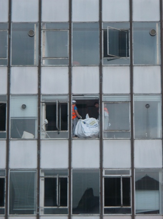 Photo shows works working at height and a large bag of rubble